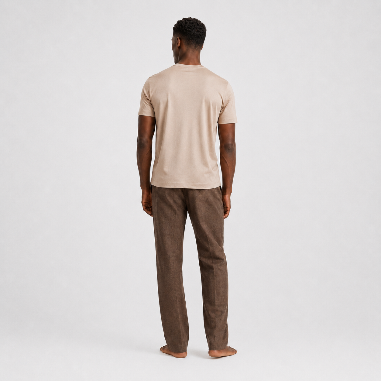 Model trägt beigefarbenes Herren T-Shirt im Clean Fit kombiniert mit einer dunklen Hose | Malviro